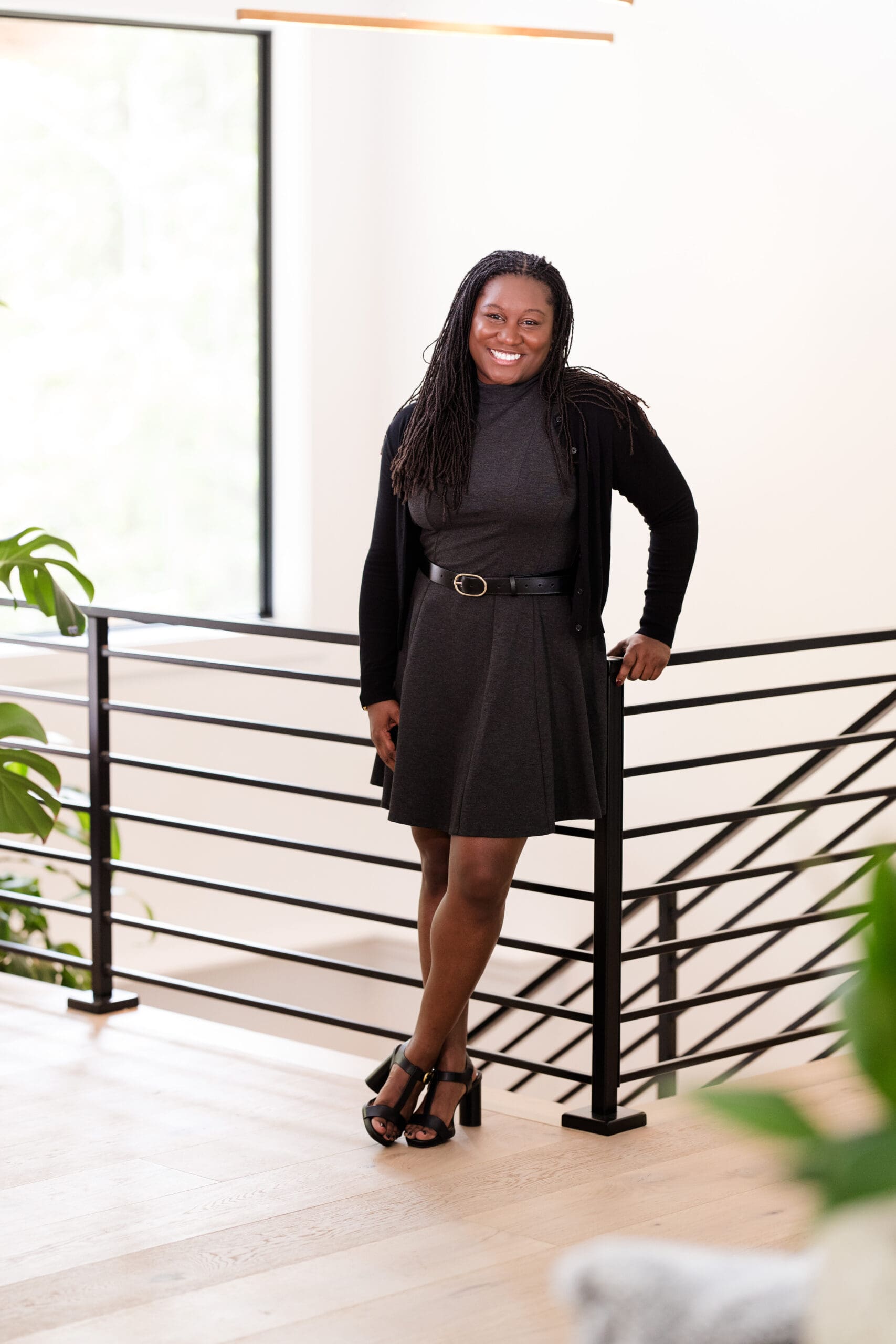 Bright and airy professional portrait of lady smiling and leaning on stair railing